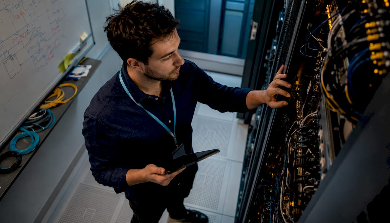 Un ingénieur spécialisé s'occupe de la gestion d’un serveur d’intelligence artificielle dans une salle technique sécurisée.