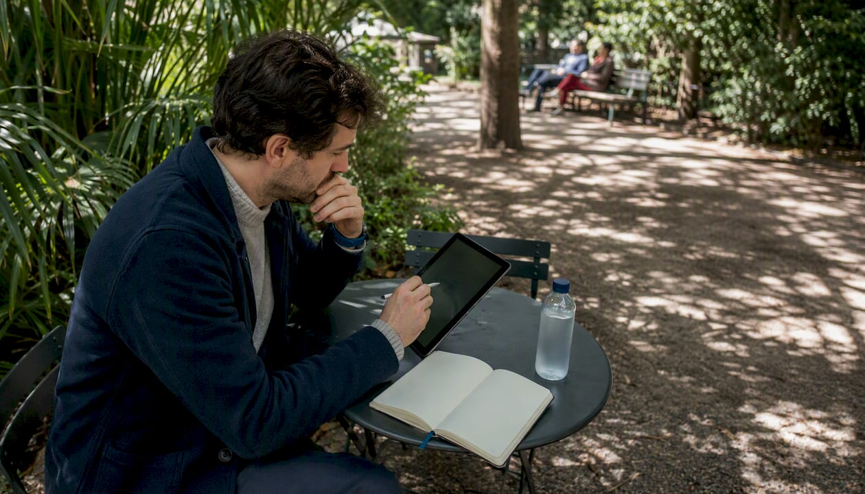 Un consultant français installé en terrasse, concentré sur sa tablette.