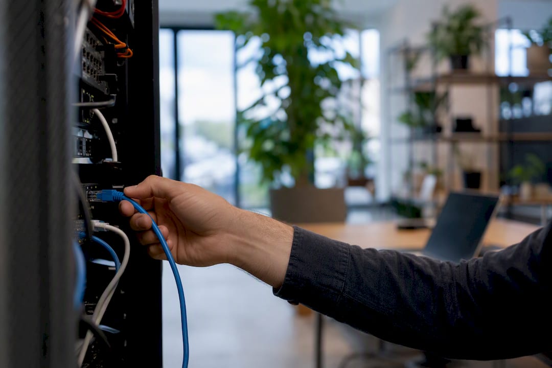 Main connectant un câble réseau à un serveur