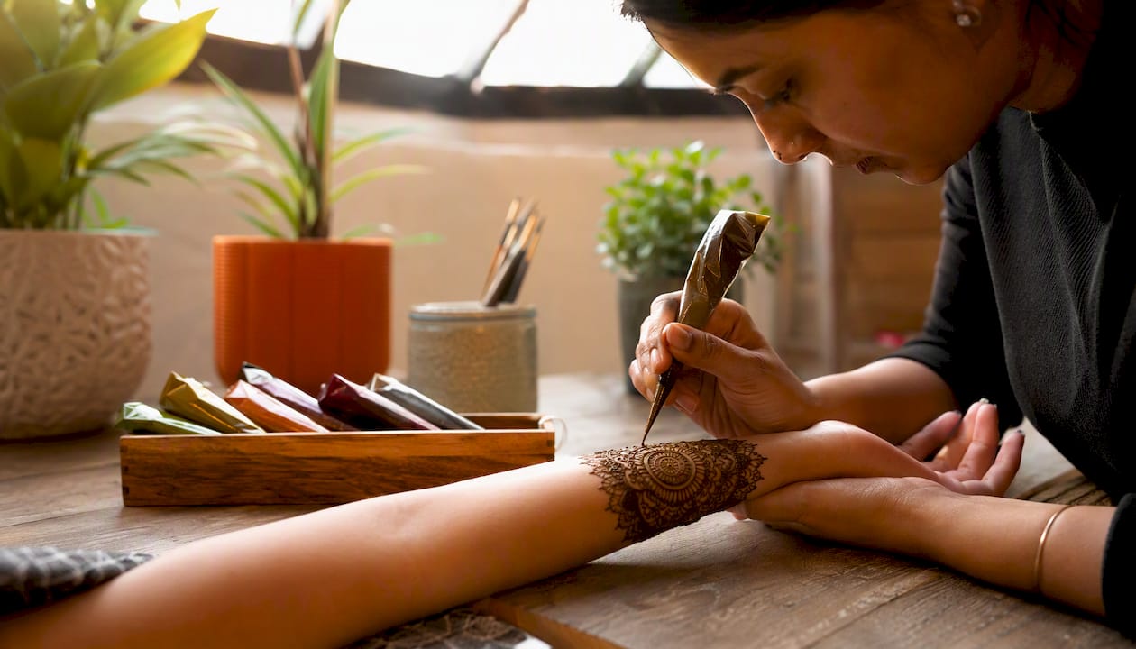 Henna artist applying henna design on arm