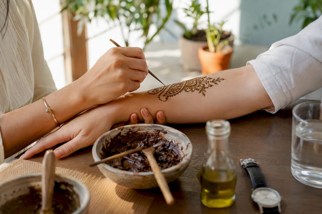 Hands applying henna art on forearm