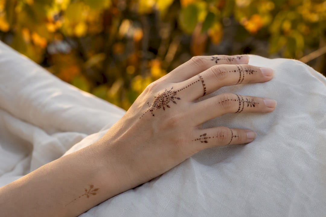Hand with minimalist finger henna designs and wrist accent