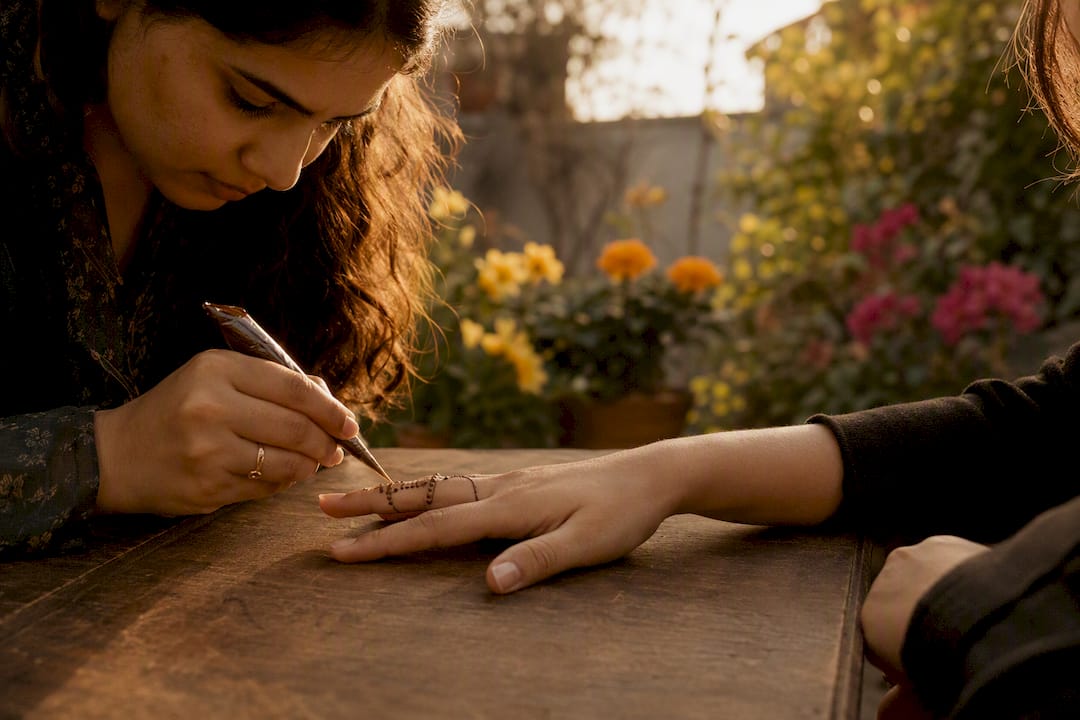 Henna artist applying thin finger henna design
