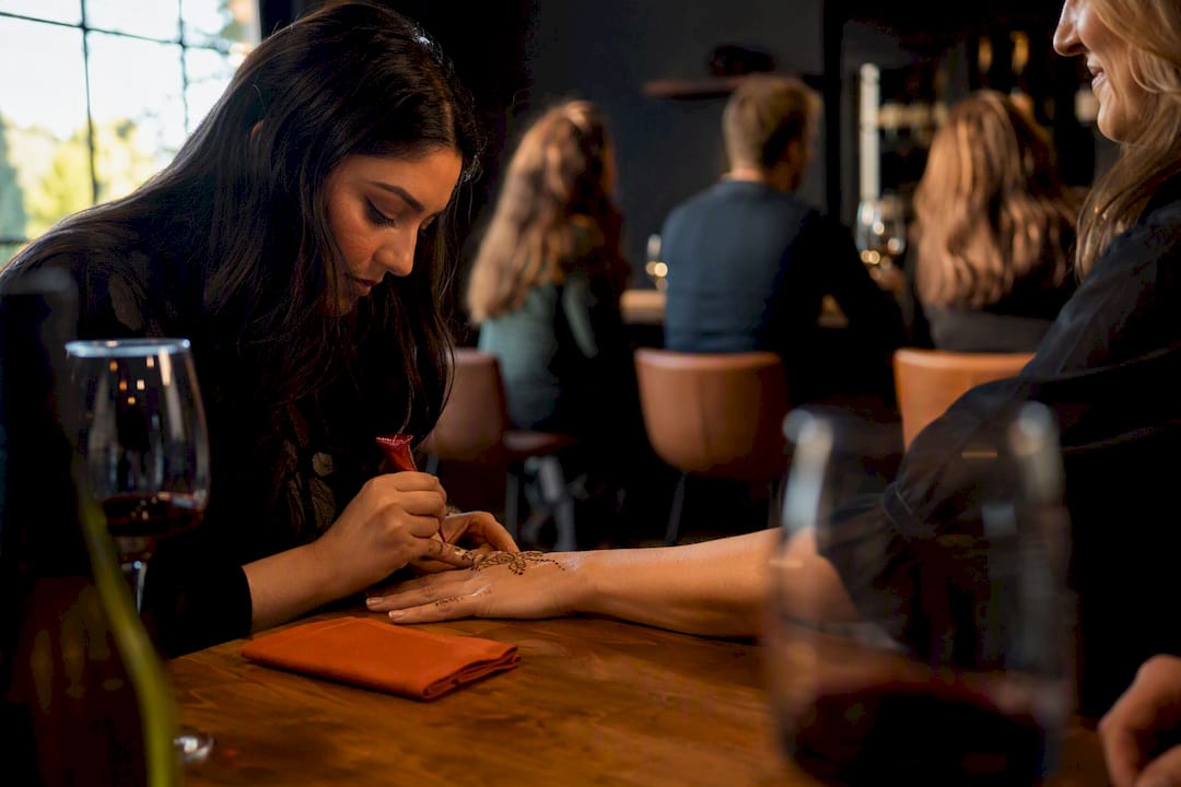 Henna artist decorating a winery guest’s hand