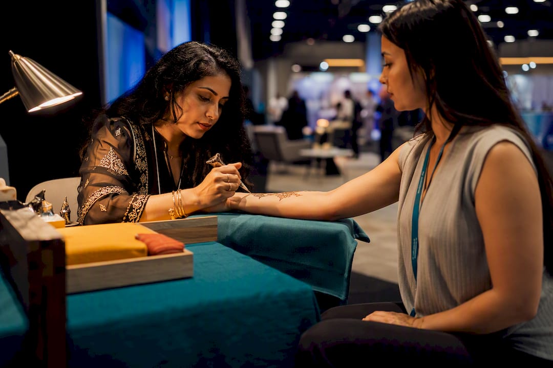 Henna artist guiding conference booth attendee