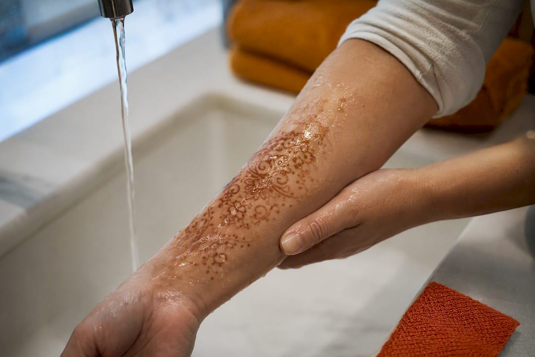 Hands rinsing henna stain from forearm