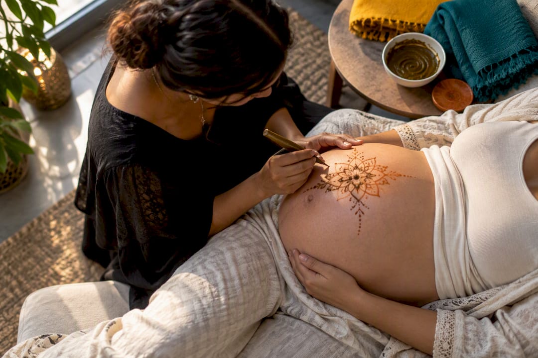 Artist applying henna to pregnant belly
