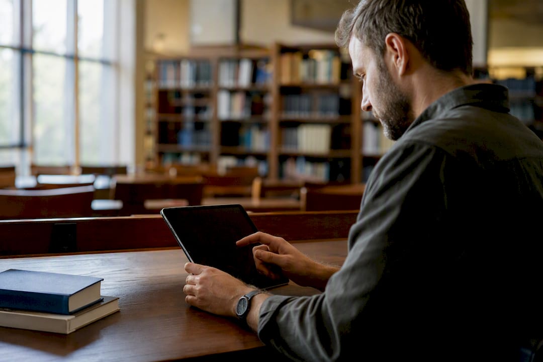 Hand selecting theology journal on tablet in library