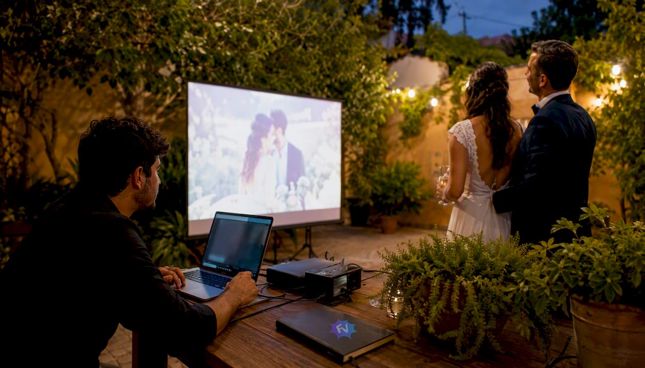 Una pareja disfruta reviviendo su boda a lo grande, viendo el vídeo proyectado en pantalla gigante.