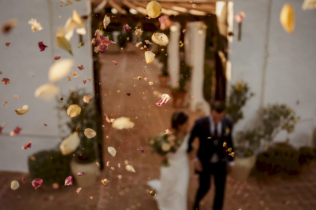 Pétalos al aire mientras los novios salen de la ceremonia