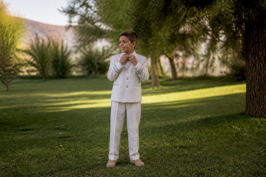 Niño ajustándose el atuendo de comunión en estudio fotográfico