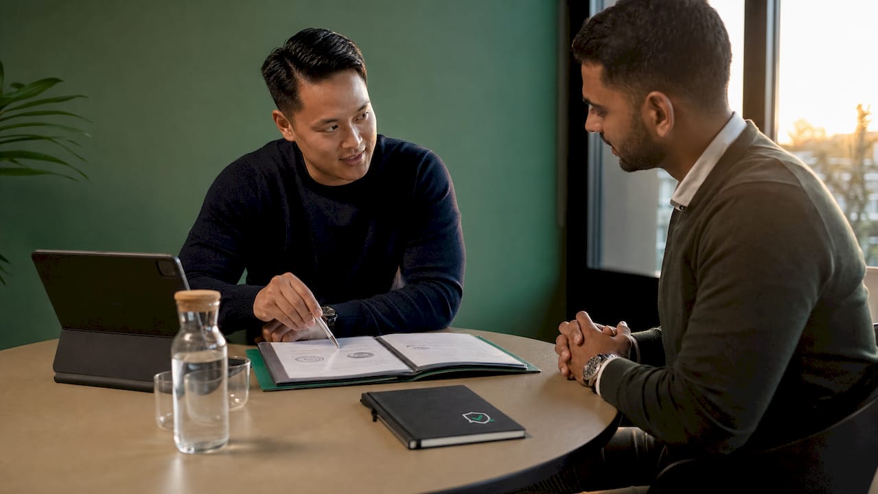 In een kantoor bespreken twee mannen samen de verschillende keurmerken en wat die betekenen voor hun werk.