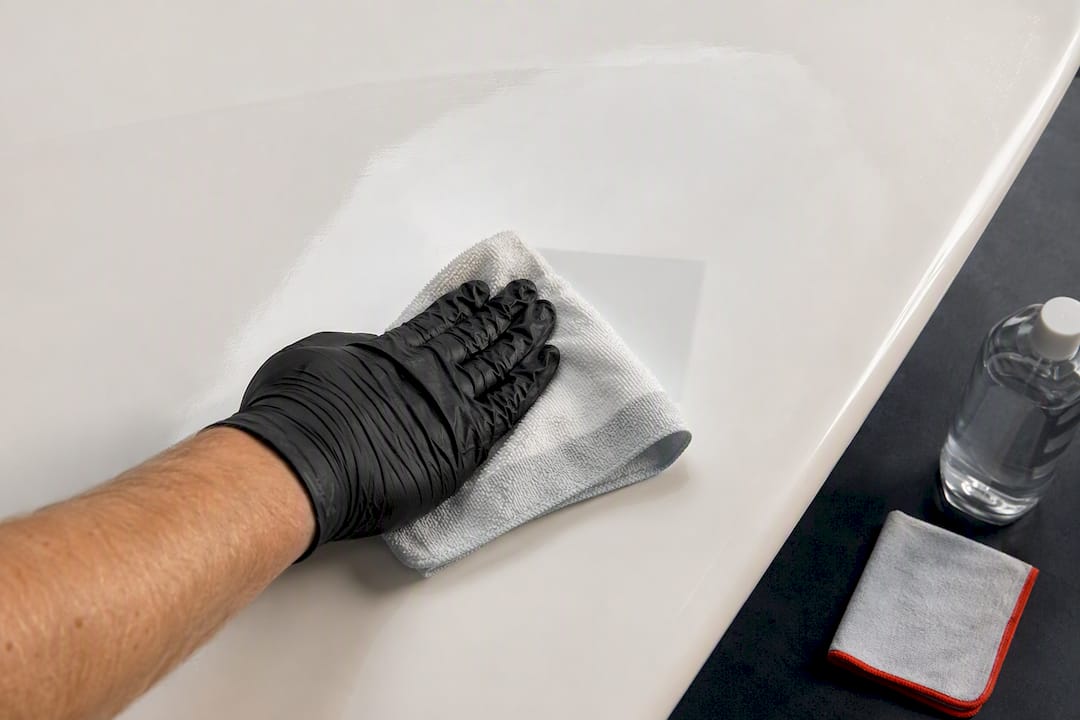 Gloved hand cleaning boat hull with alcohol