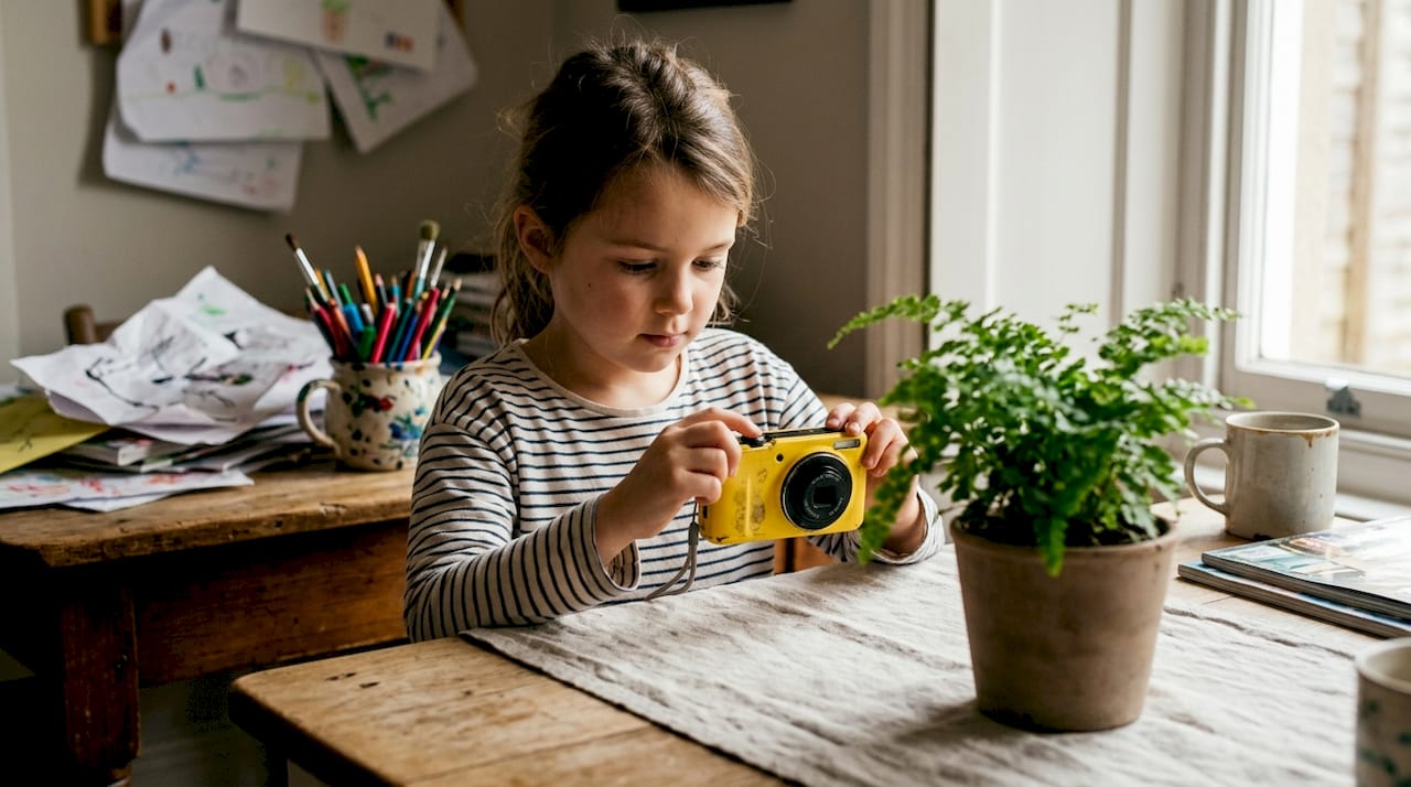 Une petite fille s'amuse à prendre des photos chez elle avec un appareil photo.