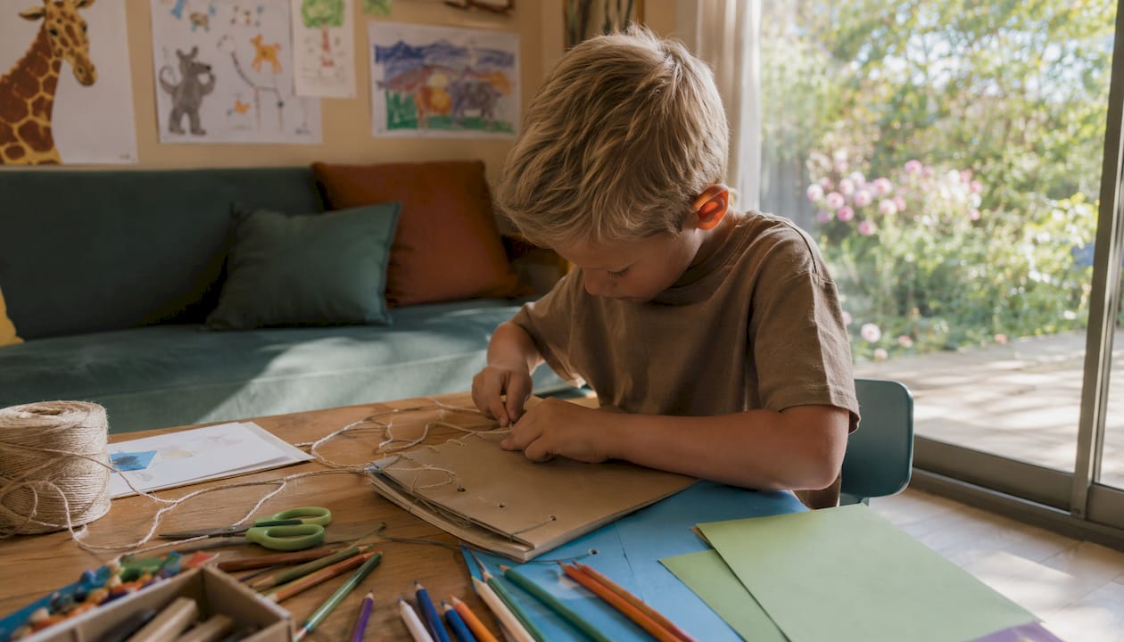 Un enfant en train de créer son propre album photo dans sa chambre