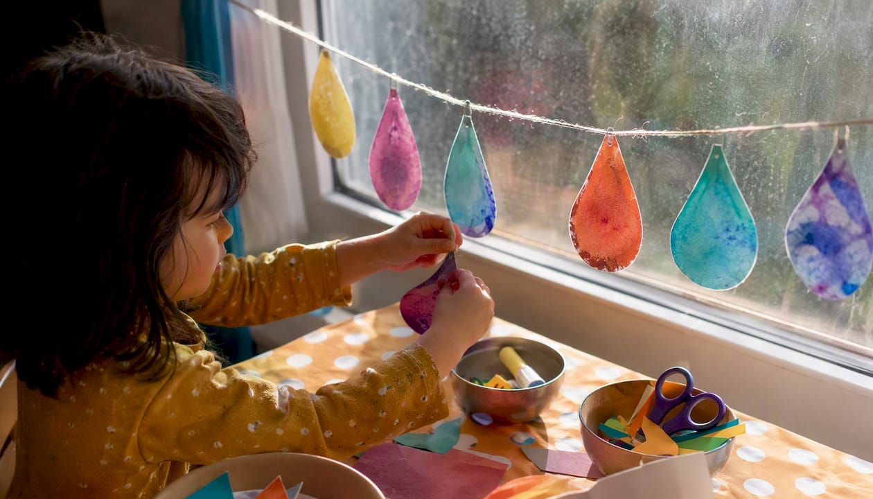 Child clipping rain-themed craft art on string