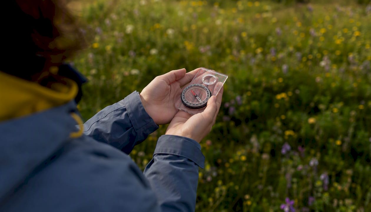 Hands holding compass flat at chest height