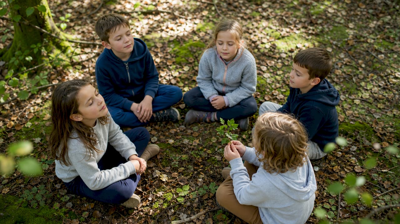 Des enfants assis, les yeux fermés, profitent du calme de la nature en écoutant les bruits environnants.