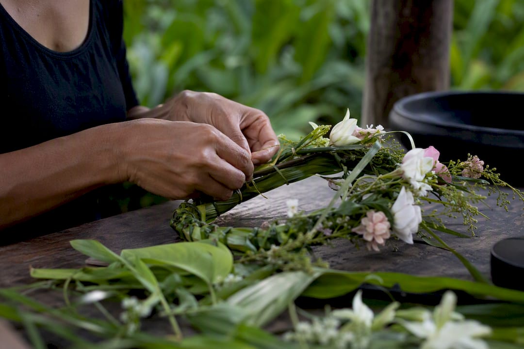 Mains fixant les tiges de fleurs sur la base de la couronne