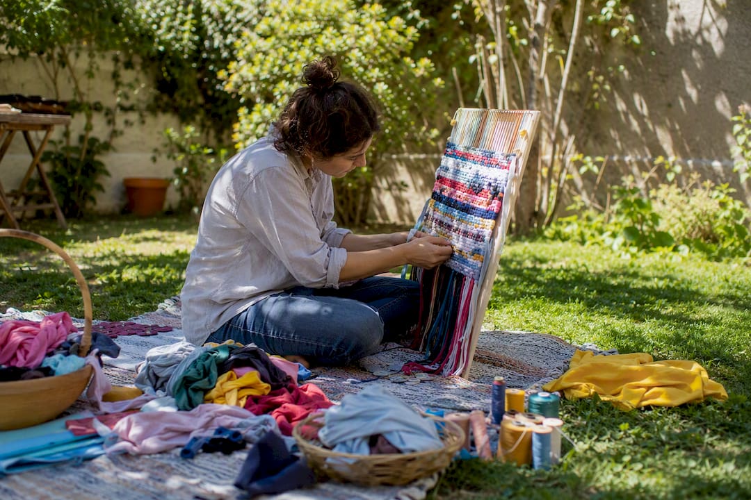 Hands weaving old t-shirt strips into wall hanging