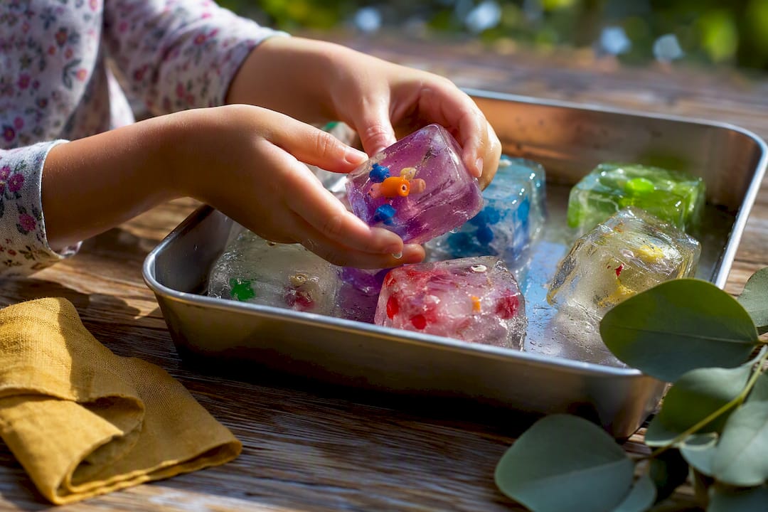 Hands exploring colorful frozen sensory cubes