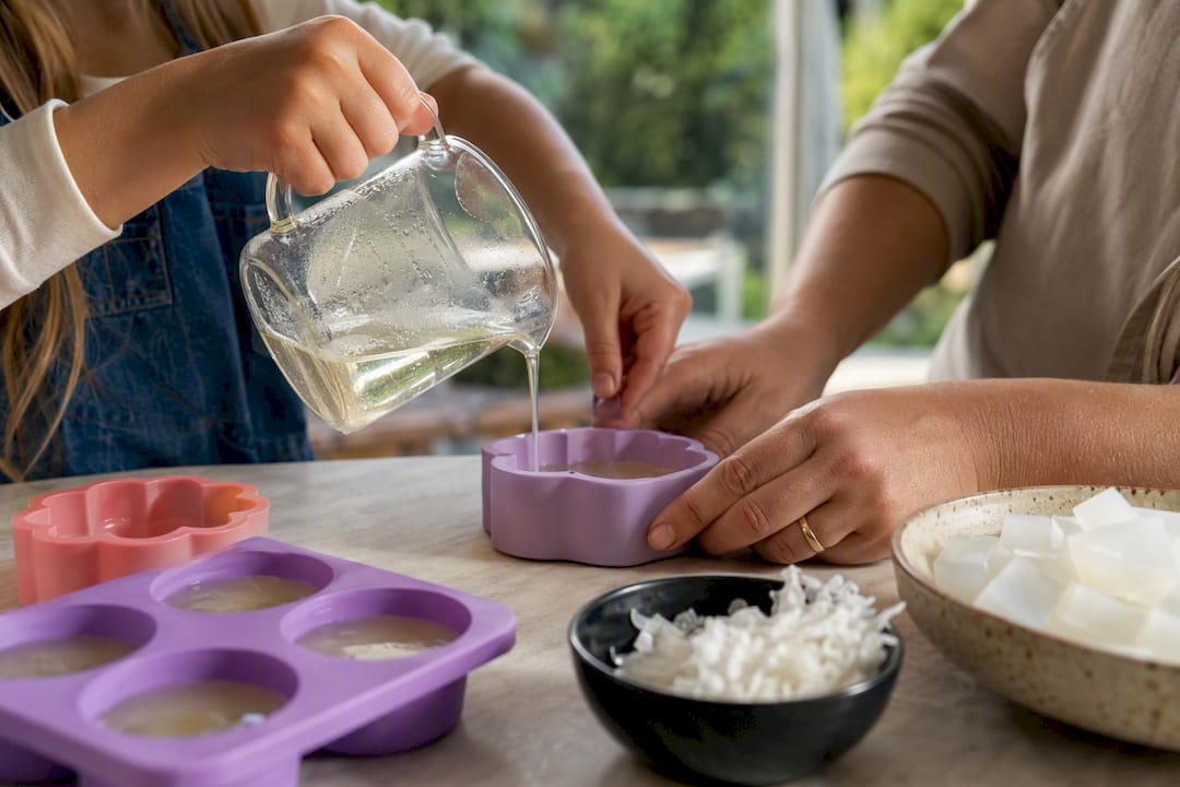 Un enfant verse du savon fondu dans un moule