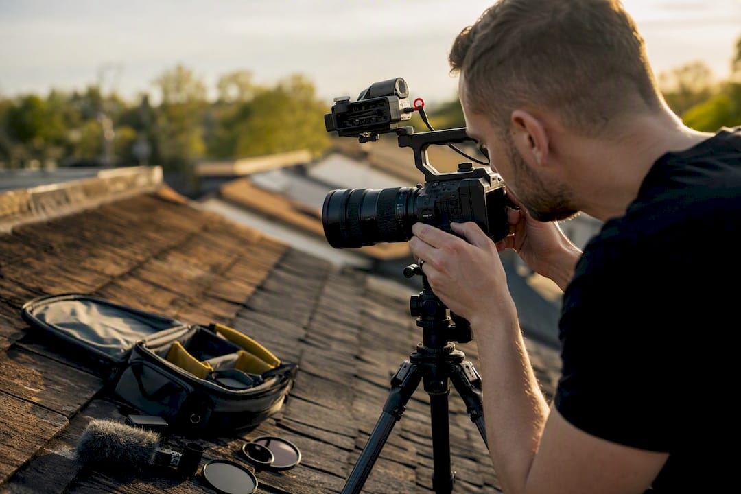 Videographer adjusting camera on roof for roofing footage