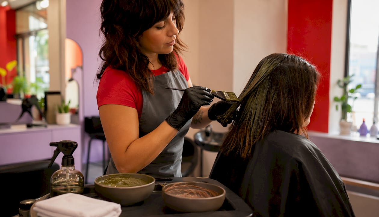 Stylist applying plant-based hair dye in salon