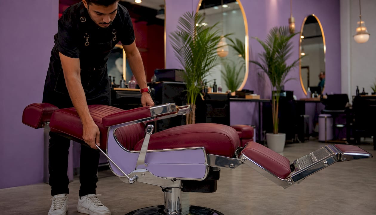 Barber adjusting reclining feature of vintage-style chair