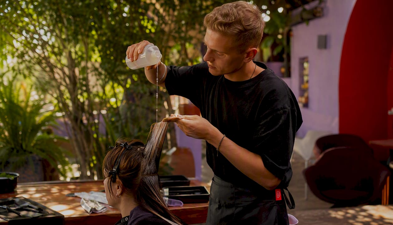 Stylist pouring liquid developer on hair roots