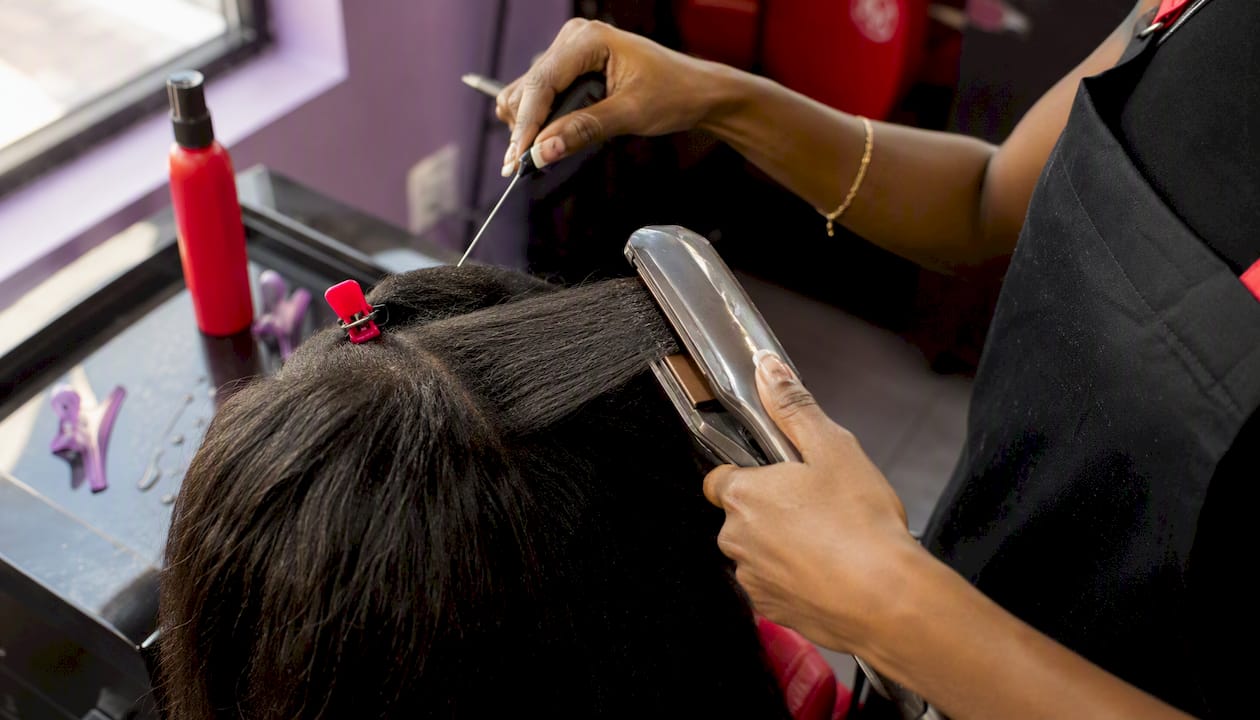Hands styling coarse hair with professional flat iron
