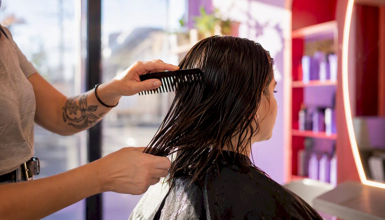 Hands combing hair after heat protectant application