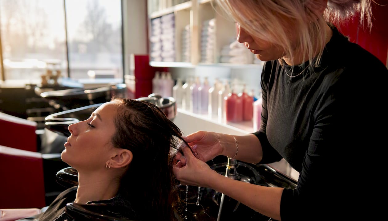 Stylist rinsing small hair section for strand test