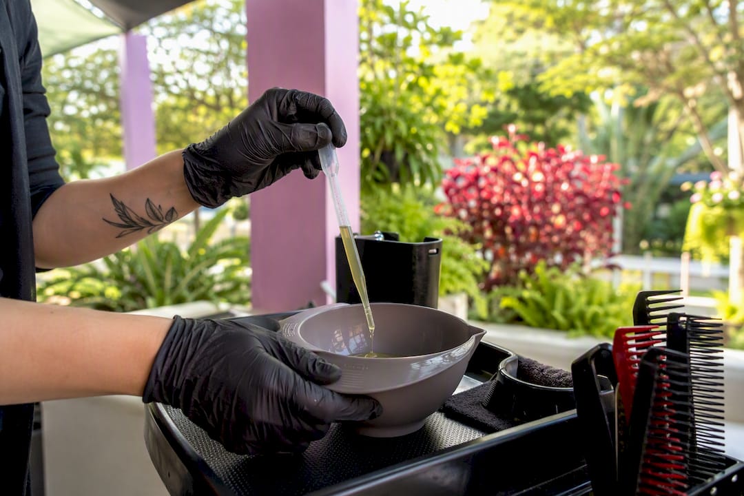 Hands dispensing hair colour with single-use pipette