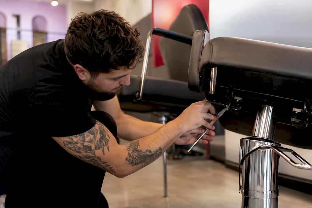 Hands repairing hydraulic lever on salon chair