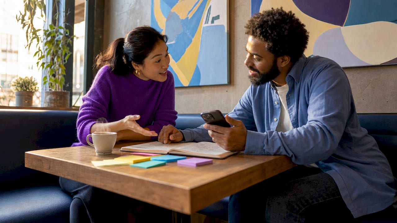 Two professionals discussing AI tools at café table