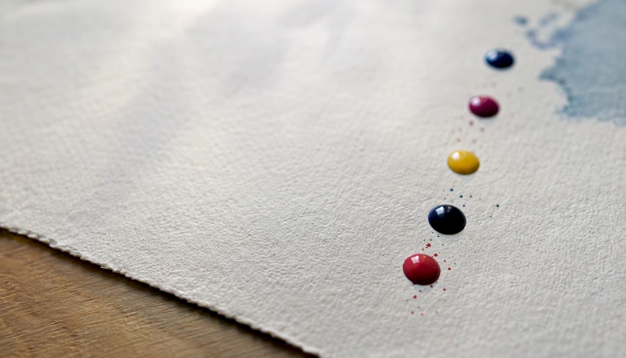 Textured cotton rag paper and pigment ink spots close-up