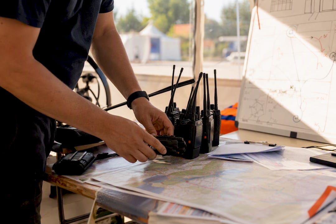 Festival security planning: the complete organiser's playbook 9 Hands setting up radios and maps in festival command post