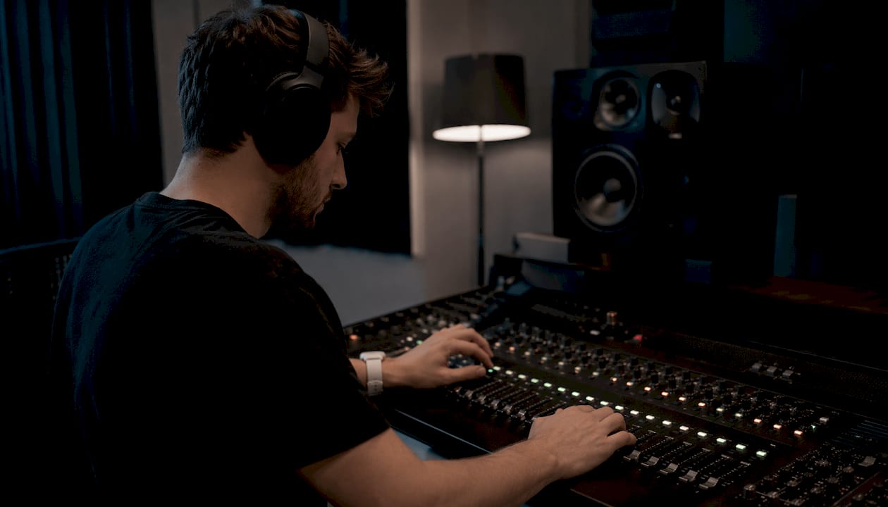 Hands adjusting audio mixer controls in studio