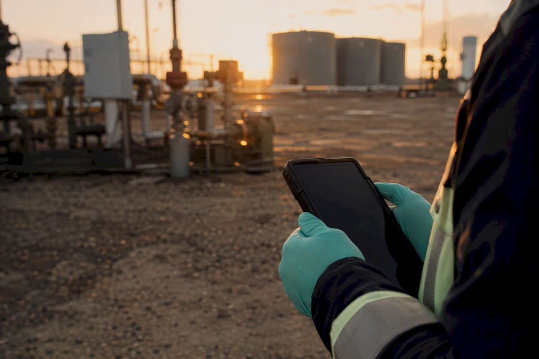 Technician holding mobile device at oilfield site