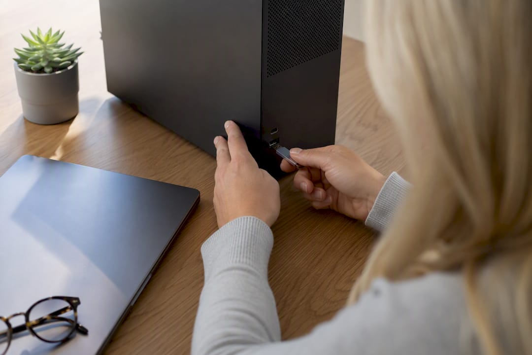 Hands inserting USB drive into computer in bright office