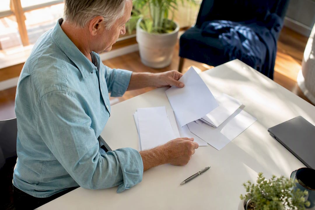 Retiree sorting medical bills at home desk