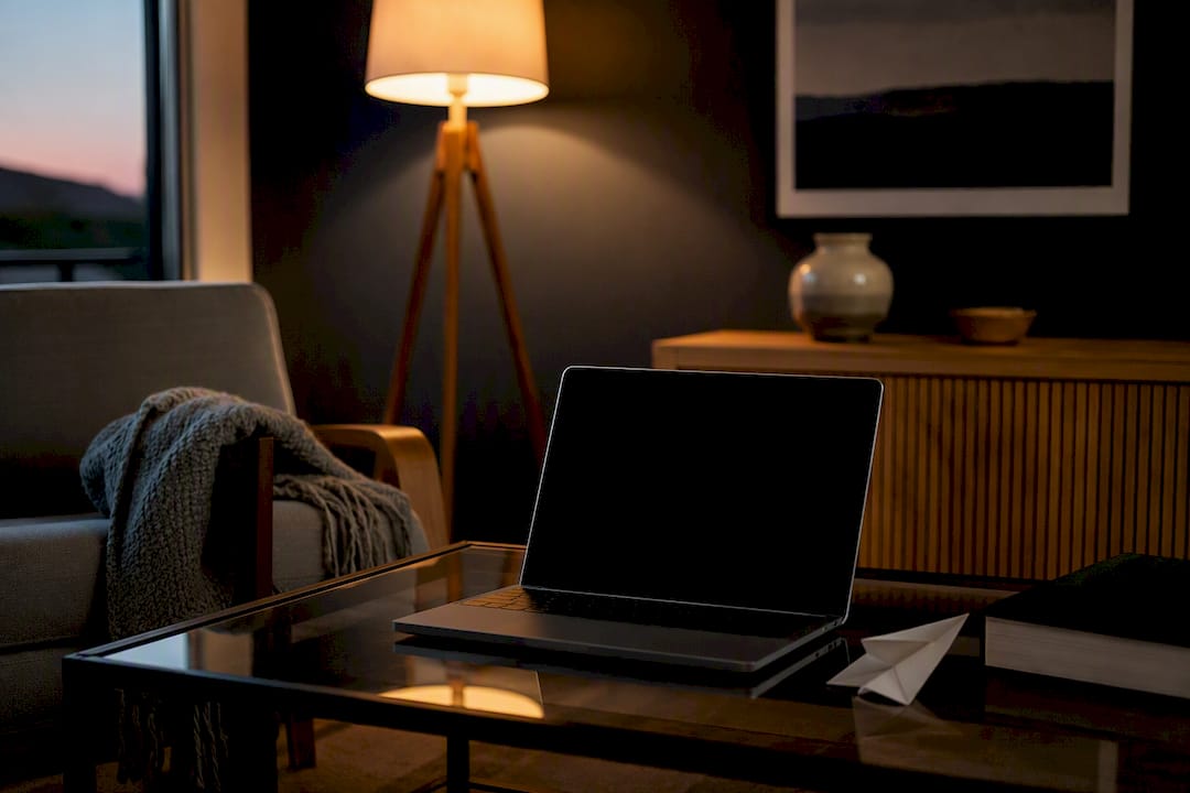 Switched-off laptop on desk with paper airplane figure