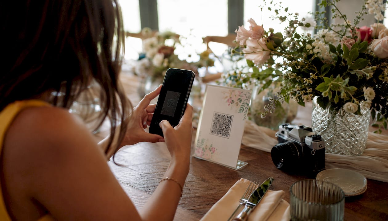 Smartphone scanning wedding QR code on table