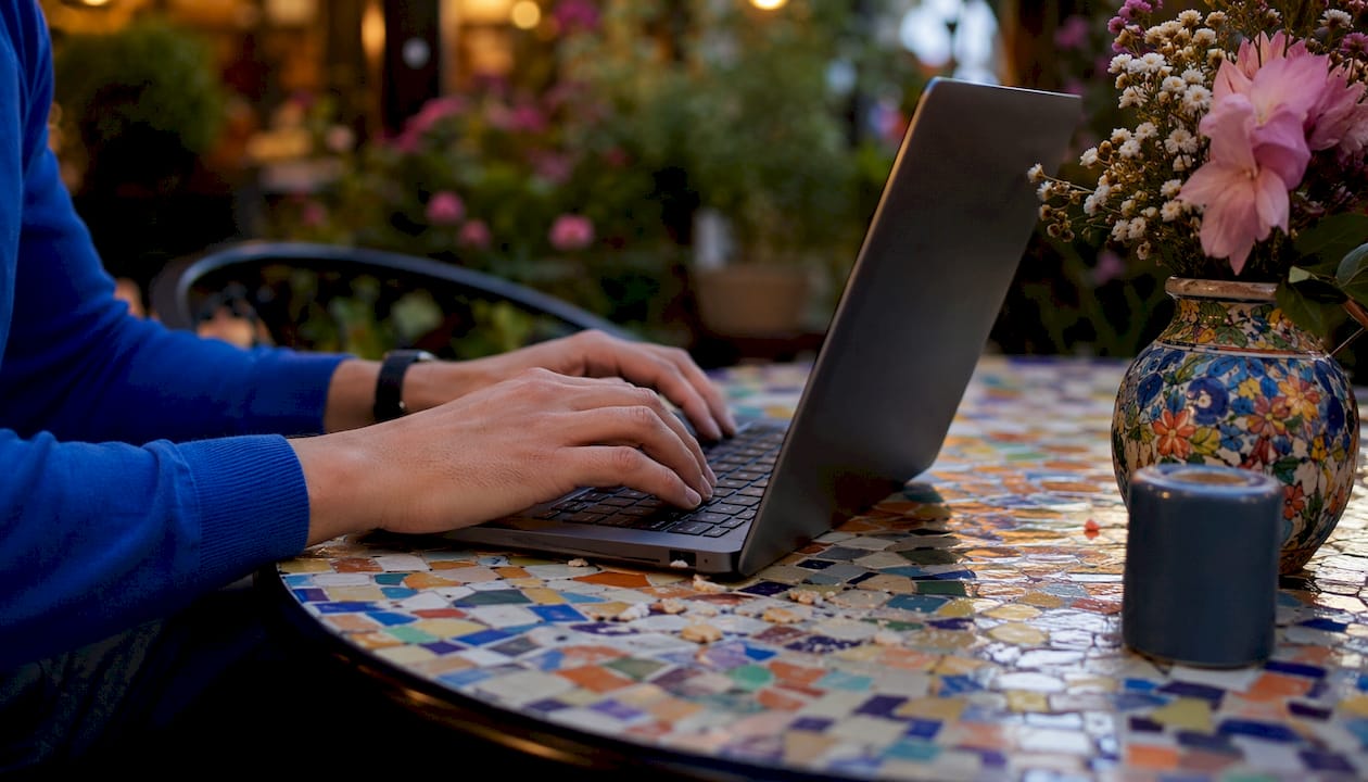 Nahaufnahme von Händen, die in einem Café auf einem Laptop tippen