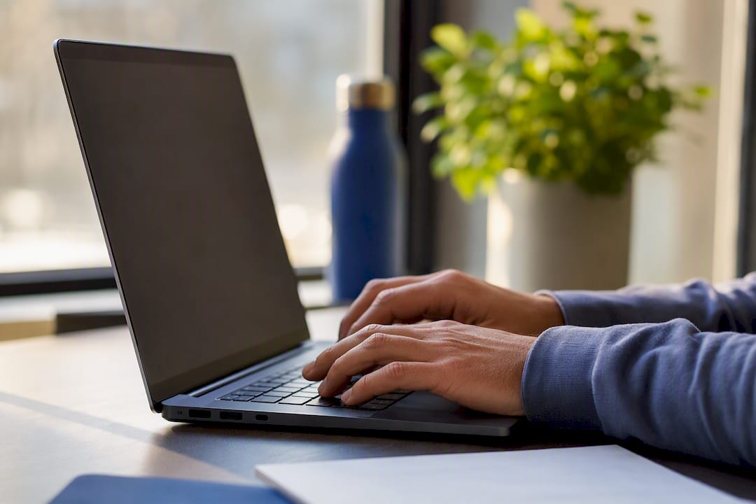 Manos escribiendo en el teclado de la laptop