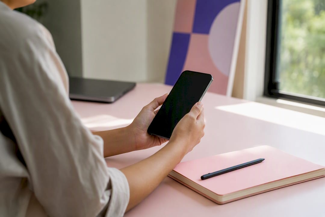 Hands holding smartphone with dark screen and analytics props