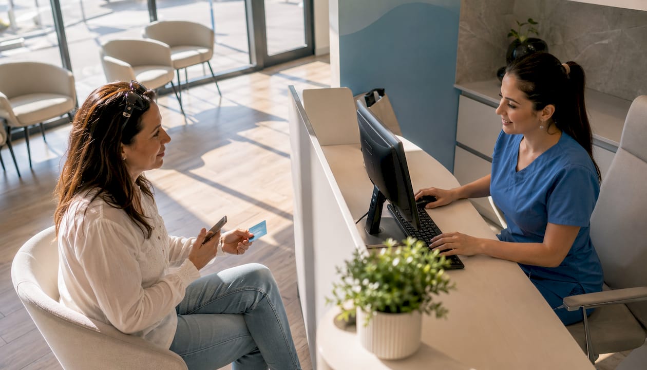 Patient providing insurance card at dental clinic reception