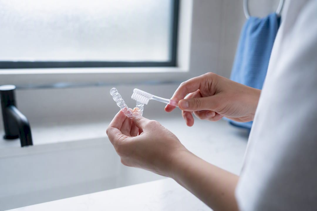 Hands brushing clear removable retainer