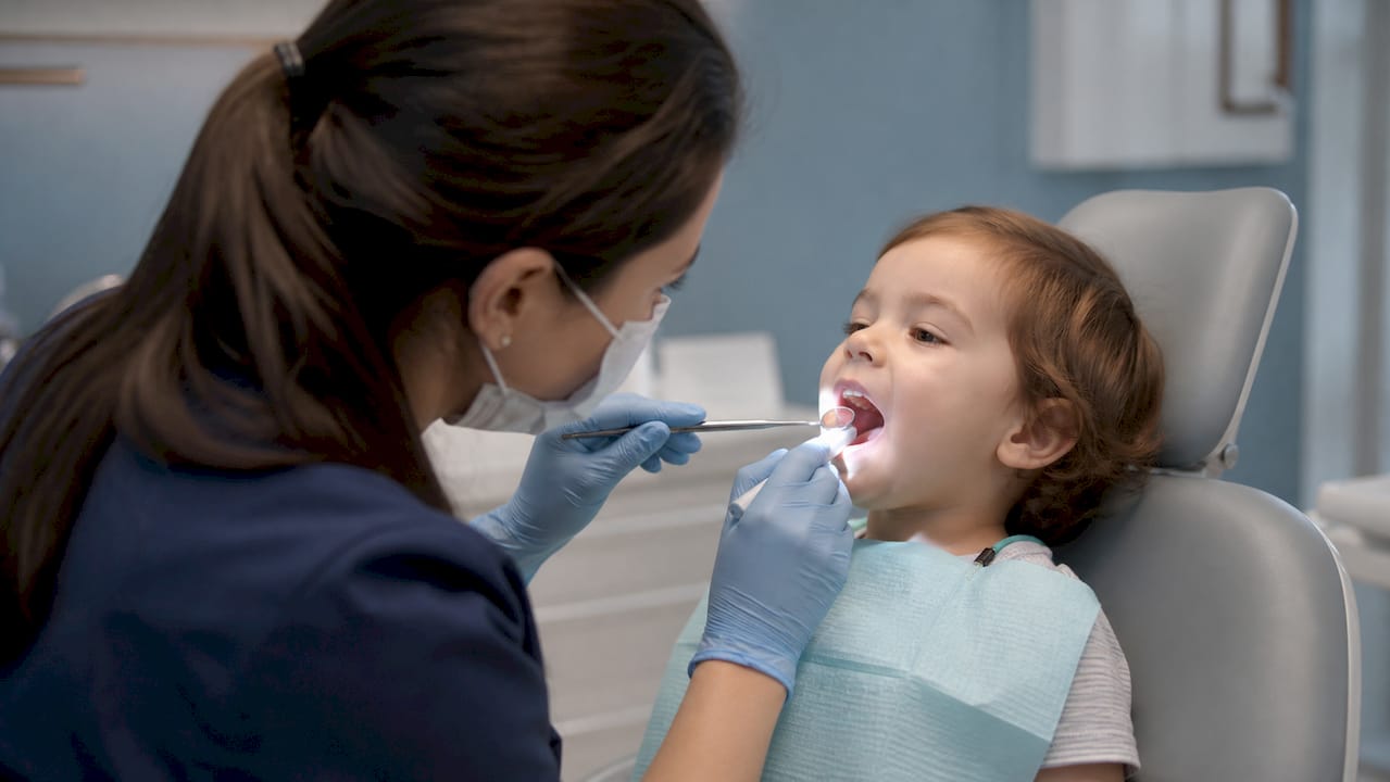Pediatric dentist visually examining toddler mouth